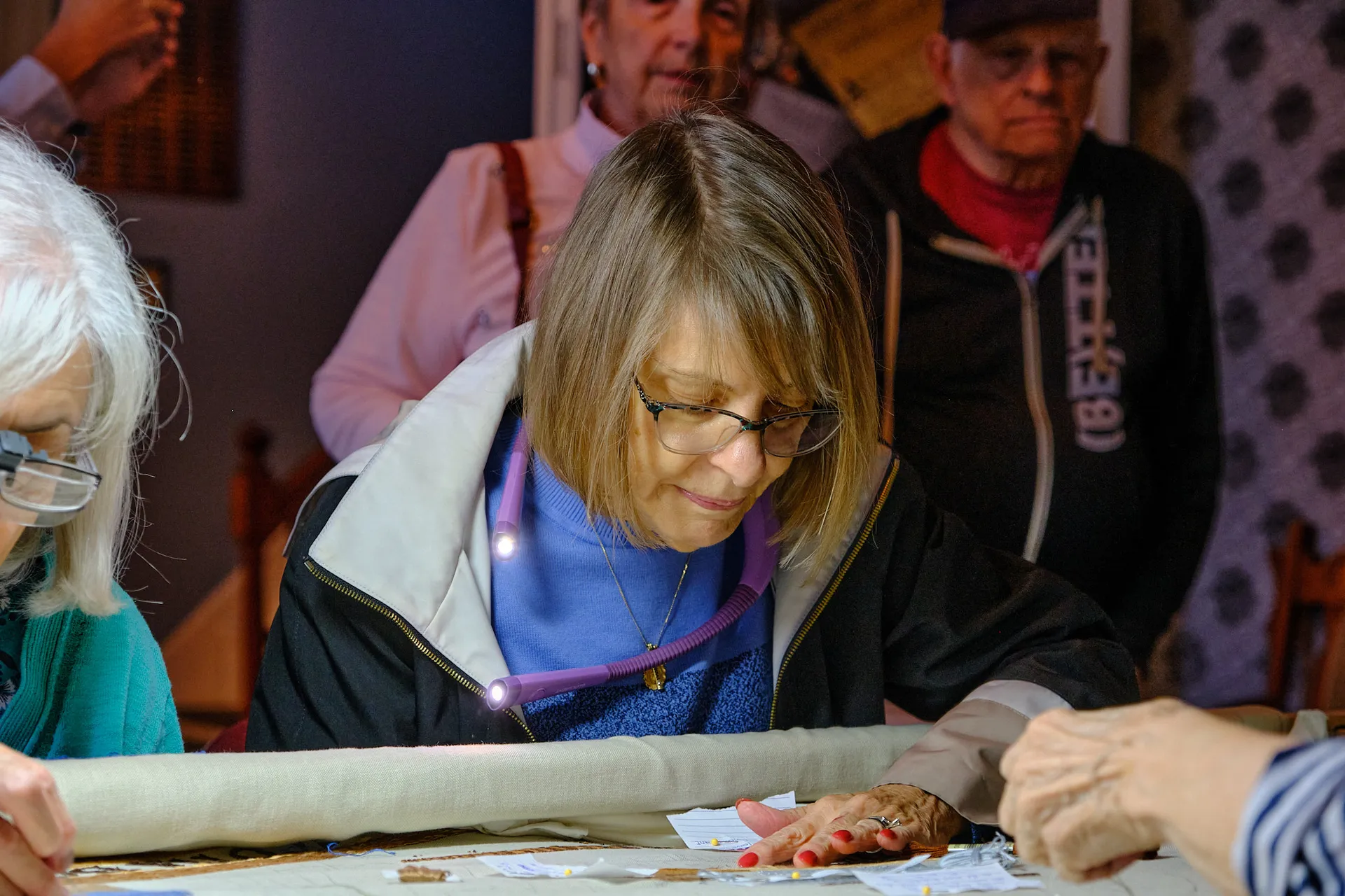 A stitcher works on the New York panel as visitors look on at a public event