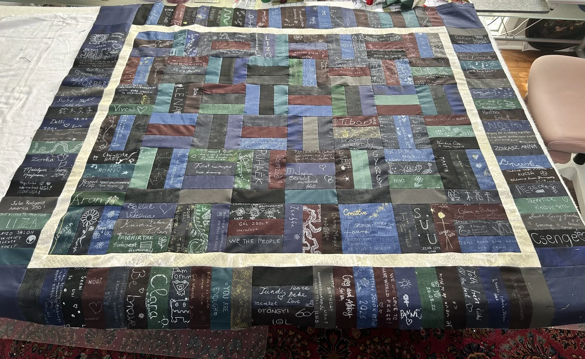 The patchwork of signed fabric rectangles, framed by its cream border